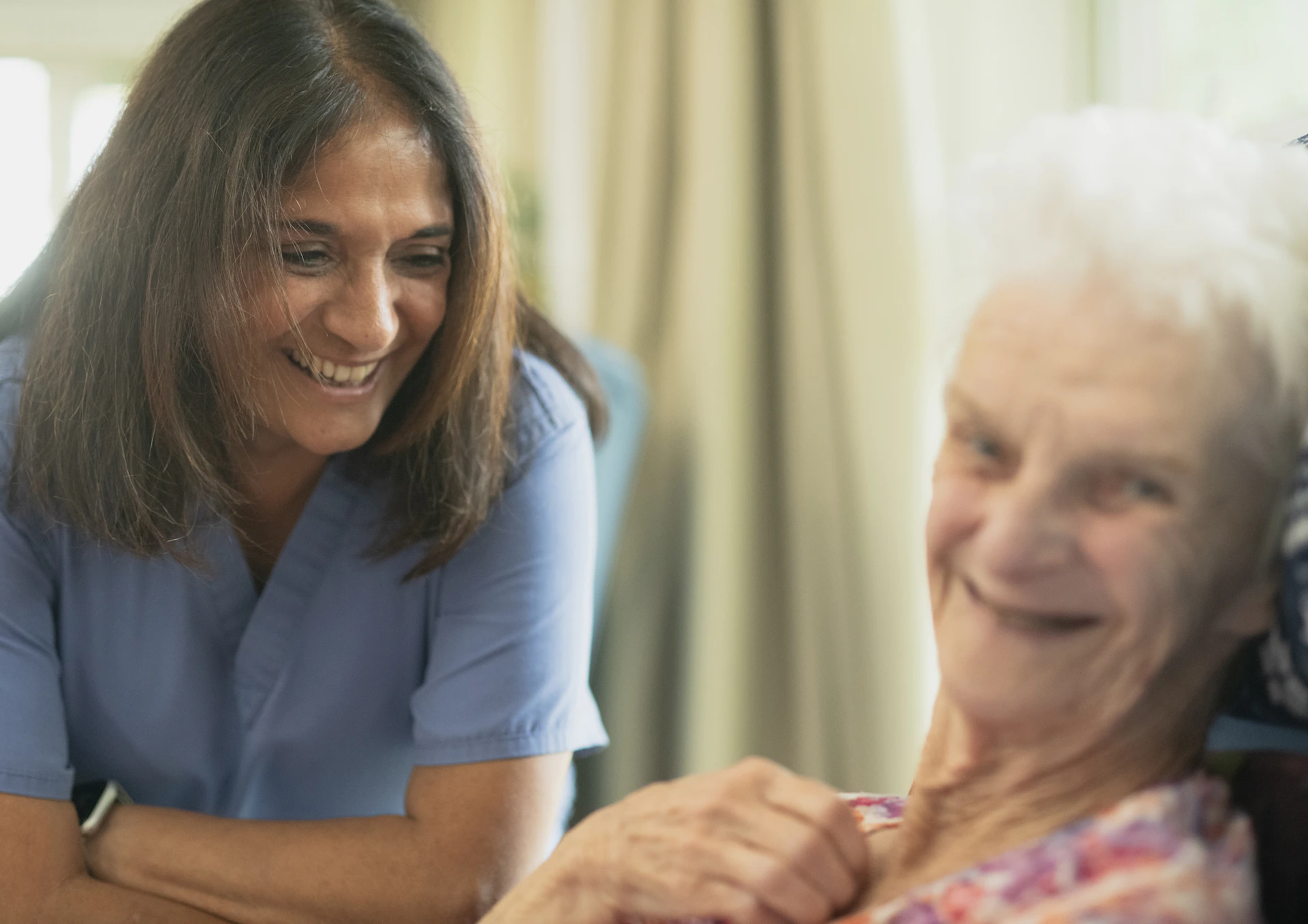 A carer smiling with an elderly client at home